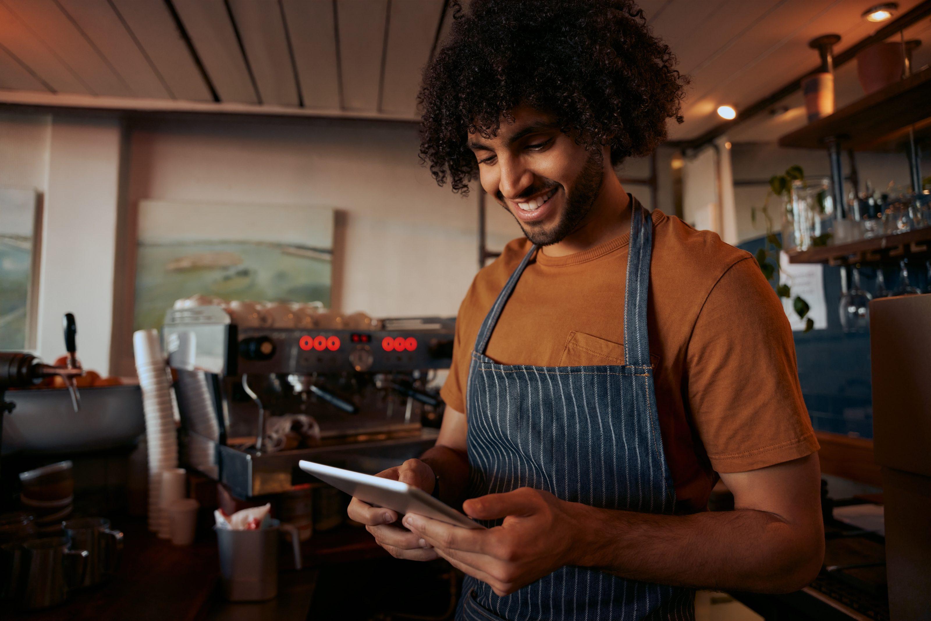 Lojista sorrindo enquanto confere um pagamento no celular